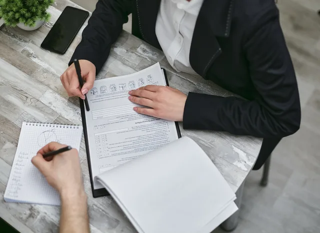 Two colleagues reviewing documents and taking notes during a business meeting. PR agencies strategy framework: agency, in-house, trial or hold